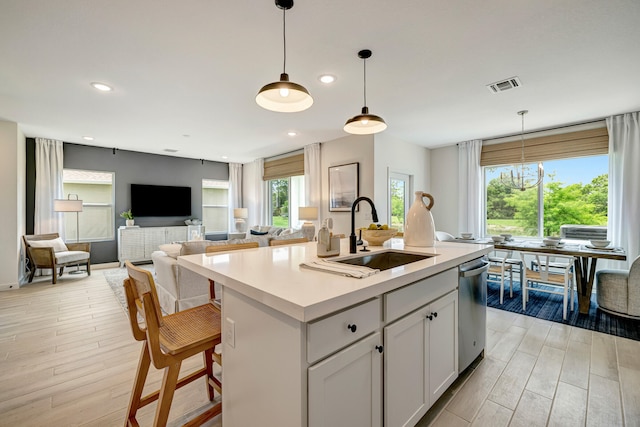 kitchen featuring plenty of natural light, sink, an island with sink, and hanging light fixtures