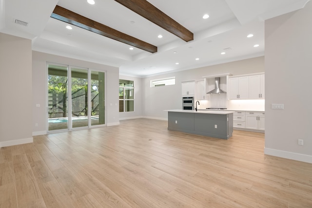 unfurnished living room with beam ceiling, sink, light hardwood / wood-style flooring, and crown molding