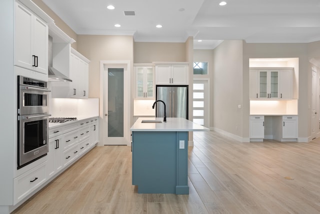 kitchen with light hardwood / wood-style flooring, white cabinets, a kitchen island with sink, and stainless steel appliances