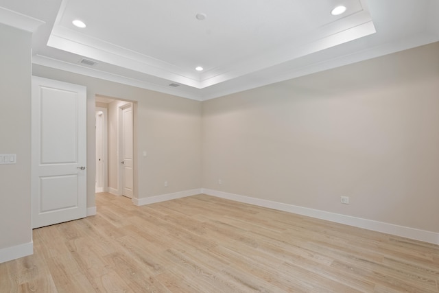 unfurnished room with light hardwood / wood-style floors and a raised ceiling