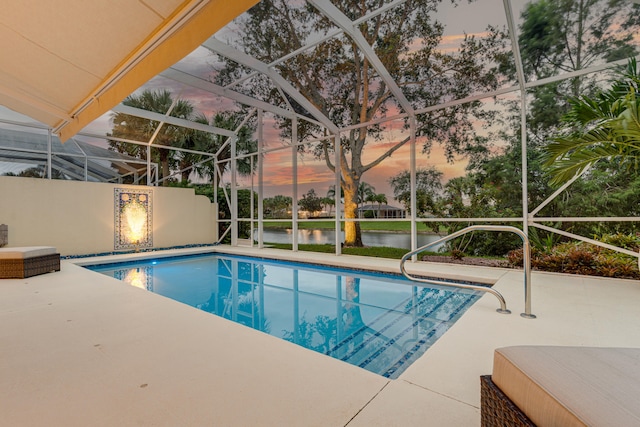 pool at dusk with a patio, a water view, and glass enclosure