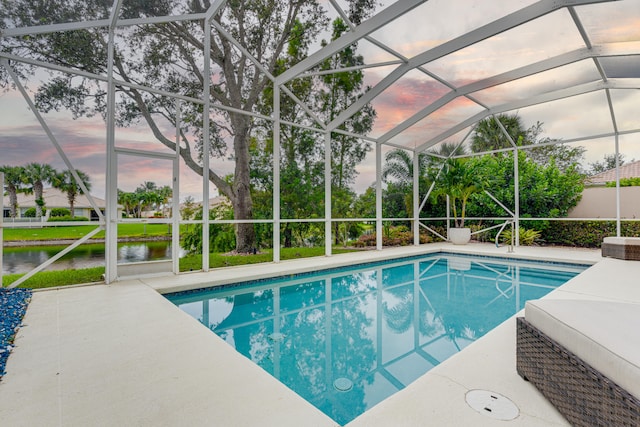 pool at dusk featuring a water view, a patio, and glass enclosure