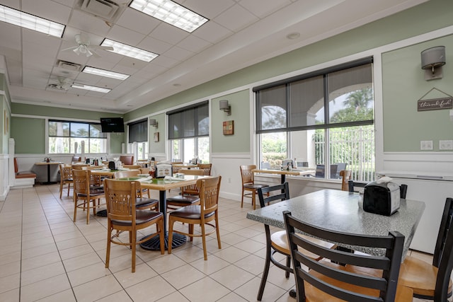 tiled dining area featuring a drop ceiling, a tray ceiling, and ceiling fan