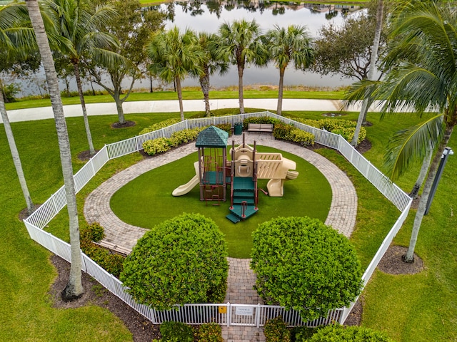 view of community featuring a playground, a yard, and a water view