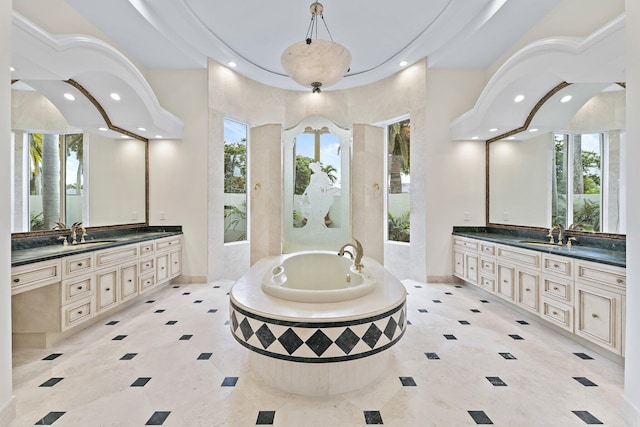 full bathroom with a wealth of natural light, two vanities, a garden tub, and recessed lighting