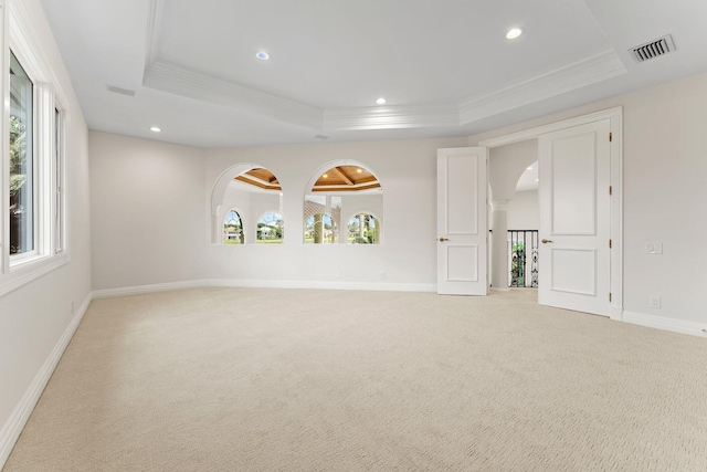 spare room featuring arched walkways, a raised ceiling, light colored carpet, and ornamental molding