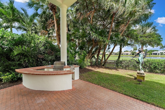 view of patio featuring an outdoor kitchen, fence, area for grilling, and a water view