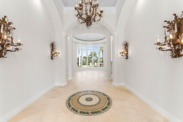 hallway with ornate columns, an inviting chandelier, ornamental molding, arched walkways, and baseboards