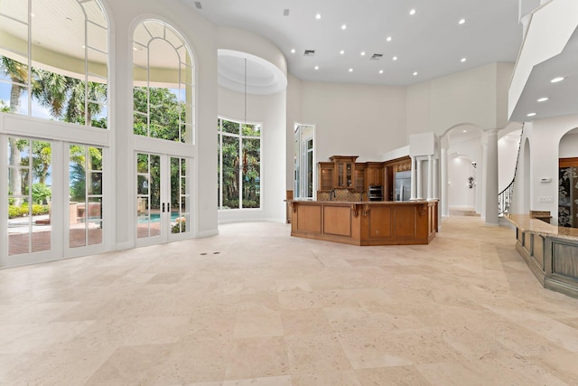 interior space featuring baseboards, a towering ceiling, visible vents, and recessed lighting