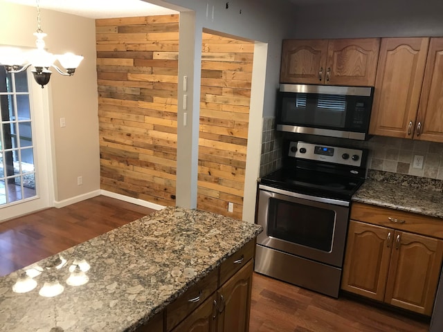 kitchen with light stone counters, backsplash, dark hardwood / wood-style floors, a notable chandelier, and stainless steel appliances