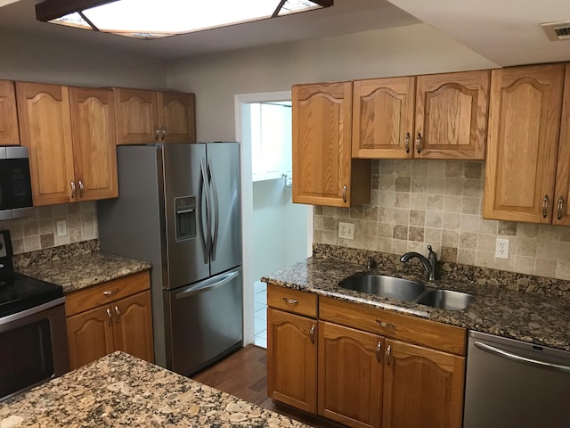 kitchen featuring stainless steel appliances, sink, and dark stone counters