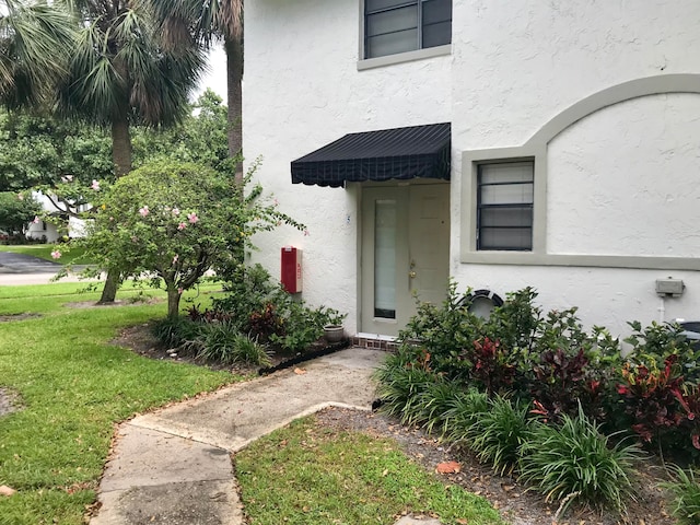 property entrance featuring a lawn