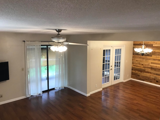 spare room with wooden walls, dark wood-type flooring, a textured ceiling, and french doors