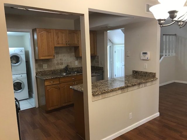 kitchen with sink, dark wood-type flooring, decorative backsplash, and an inviting chandelier