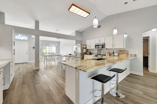 kitchen featuring kitchen peninsula, stainless steel appliances, sink, pendant lighting, and white cabinets