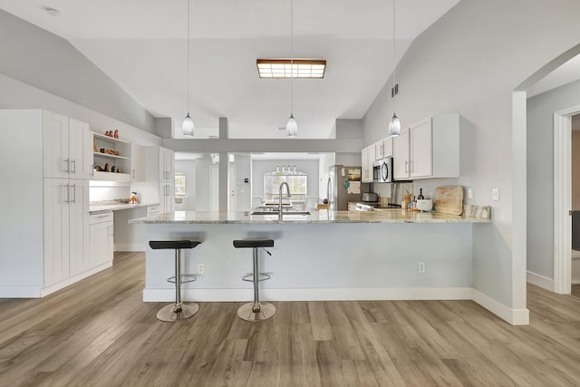 kitchen with lofted ceiling, light hardwood / wood-style flooring, kitchen peninsula, white cabinets, and appliances with stainless steel finishes