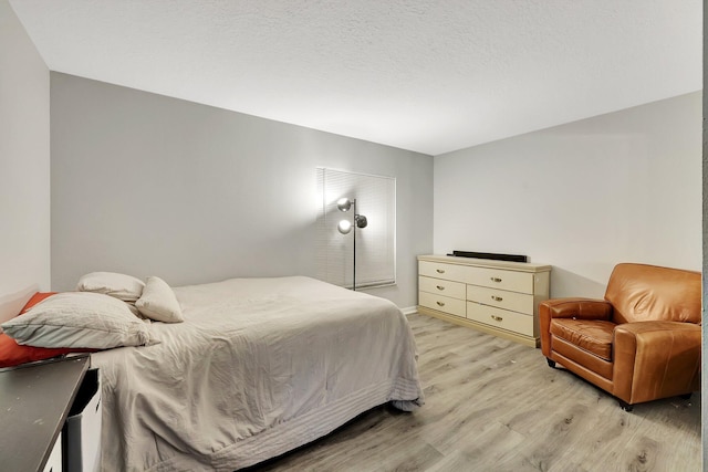 bedroom with light hardwood / wood-style flooring and a textured ceiling