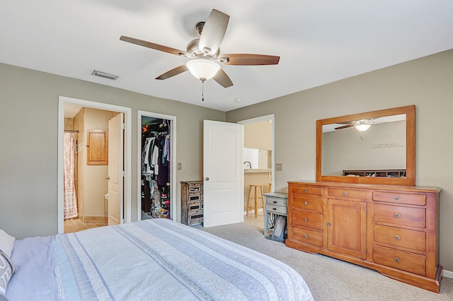 carpeted bedroom with connected bathroom, a closet, a spacious closet, and ceiling fan