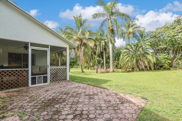 view of yard featuring a sunroom, ceiling fan, and a patio