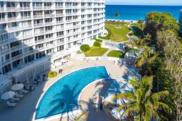 view of swimming pool featuring a patio, a yard, and a water view