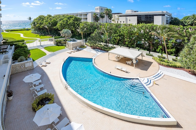 view of swimming pool featuring a patio area, a yard, and a water view