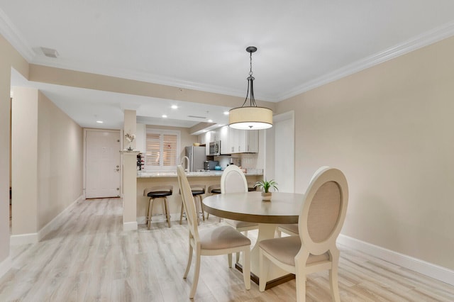 dining area with light hardwood / wood-style floors and crown molding