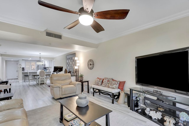 living room featuring ornamental molding, light wood-type flooring, and ceiling fan