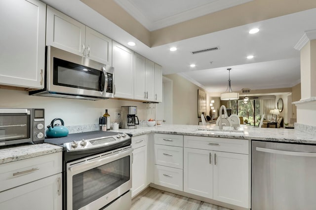 kitchen featuring stainless steel appliances, ornamental molding, sink, and white cabinets