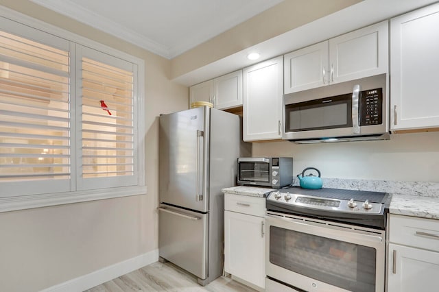 kitchen featuring ornamental molding, white cabinets, stainless steel appliances, and light stone counters