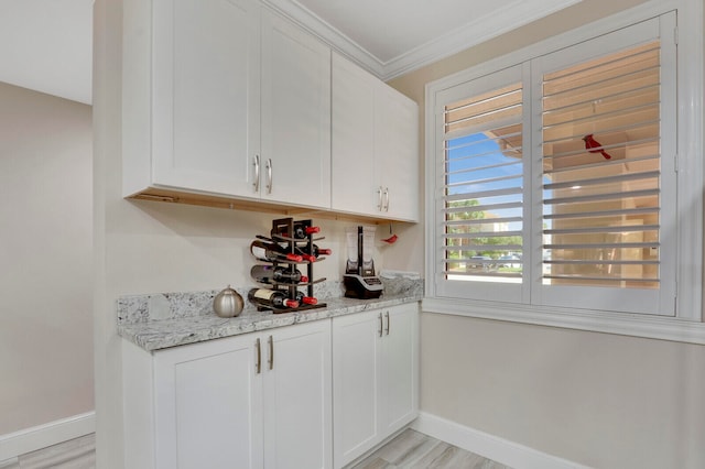 bar with crown molding, white cabinetry, light stone counters, and light hardwood / wood-style floors