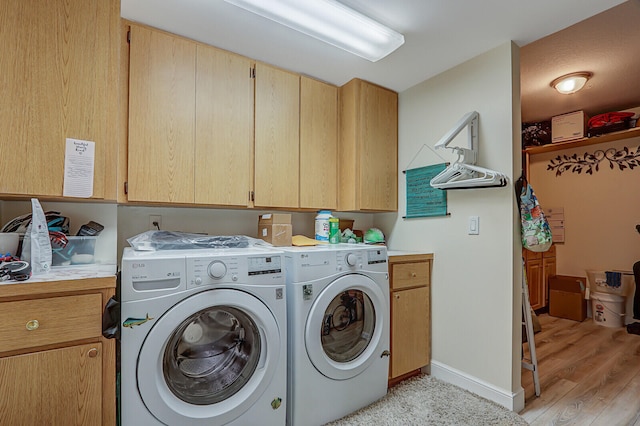 washroom with light hardwood / wood-style flooring, independent washer and dryer, and cabinets