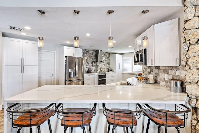 kitchen featuring white cabinets, kitchen peninsula, stainless steel appliances, and decorative light fixtures