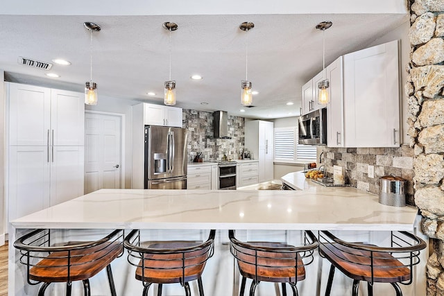 kitchen featuring white cabinets, appliances with stainless steel finishes, a peninsula, recessed lighting, and decorative backsplash
