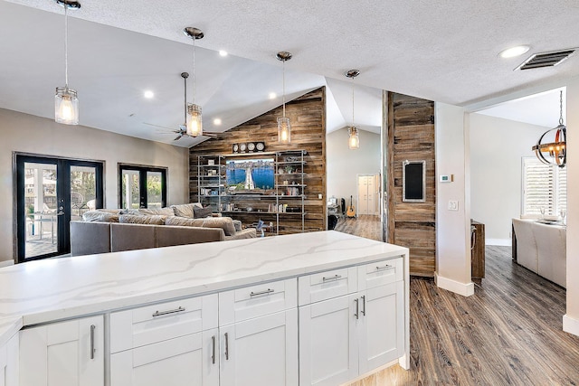 kitchen with dark wood-style flooring, visible vents, baseboards, open floor plan, and vaulted ceiling