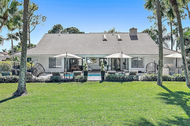rear view of house with a lawn, a tiled roof, a chimney, and outdoor lounge area
