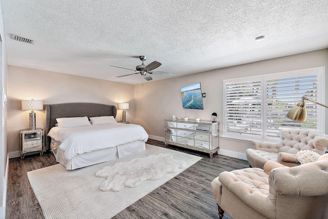 bedroom with visible vents, baseboards, dark wood-type flooring, a textured ceiling, and a ceiling fan