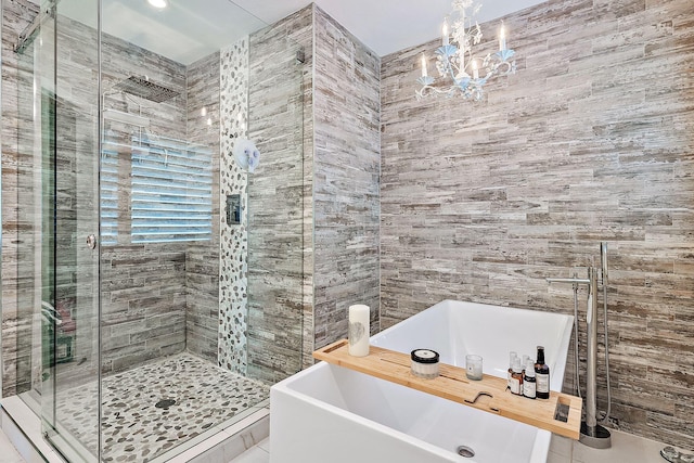 bathroom featuring a freestanding tub, a stall shower, tile walls, and a chandelier