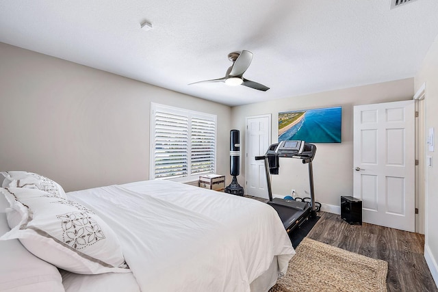 bedroom with visible vents, wood finished floors, baseboards, ceiling fan, and a textured ceiling