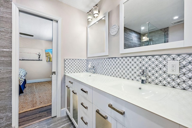 bathroom featuring vanity, decorative backsplash, hardwood / wood-style floors, and a shower