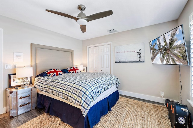 bedroom with a ceiling fan, baseboards, wood finished floors, visible vents, and a closet