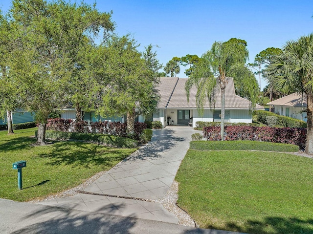 view of front of property with french doors, driveway, a tiled roof, and a front yard