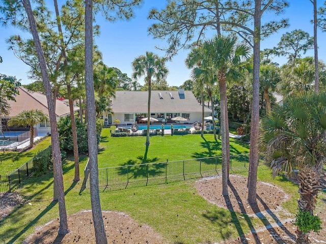 view of community featuring a fenced backyard, a pool, and a yard