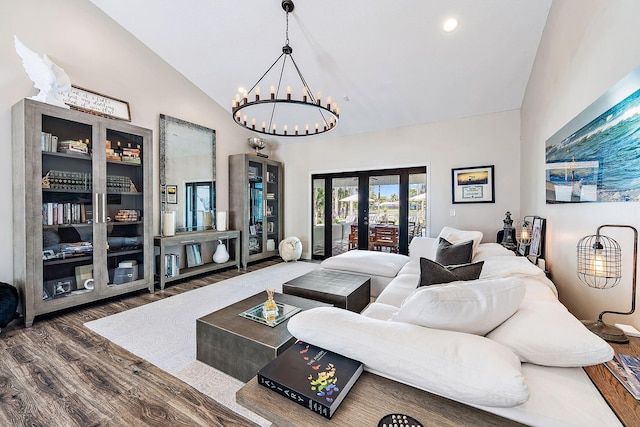 living room featuring an inviting chandelier, lofted ceiling, french doors, and dark wood-type flooring