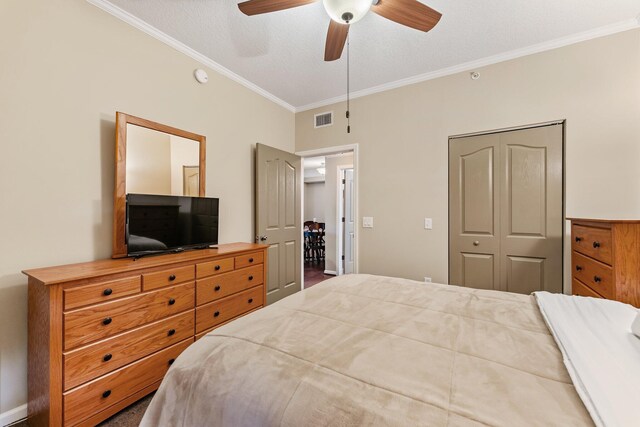 bedroom featuring a textured ceiling, a ceiling fan, visible vents, a closet, and crown molding