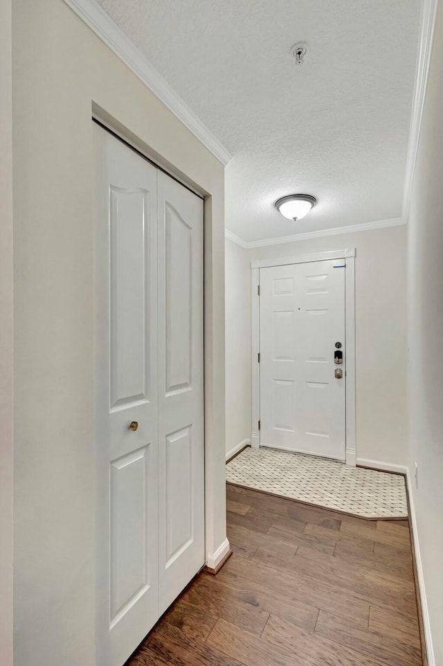 doorway to outside featuring dark wood-style floors, a textured ceiling, baseboards, and crown molding