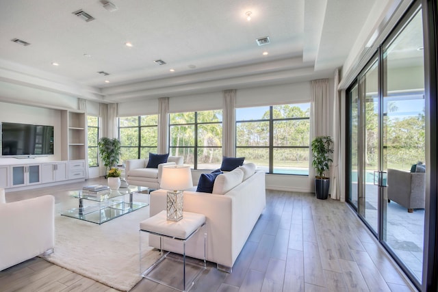 living room featuring light wood-type flooring, a tray ceiling, and a textured ceiling