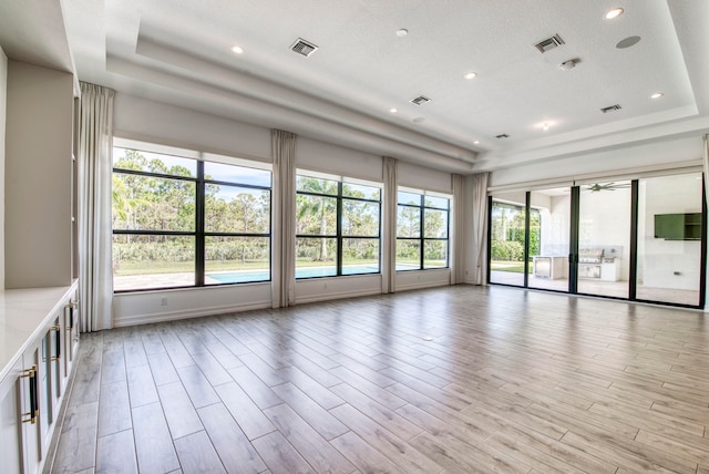 spare room featuring a tray ceiling and light hardwood / wood-style floors