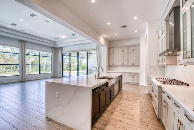 kitchen featuring light hardwood / wood-style flooring, wall chimney range hood, sink, and white cabinets