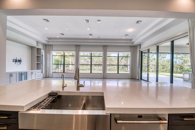 kitchen with sink, light stone counters, and a tray ceiling