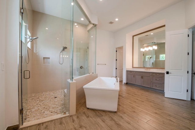 bathroom with hardwood / wood-style floors, vanity, and separate shower and tub